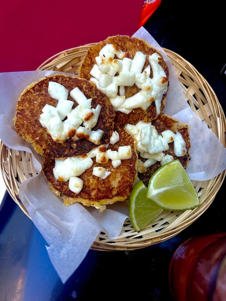 Arepas con queso servies dans un panier avec quartiers de citron vert