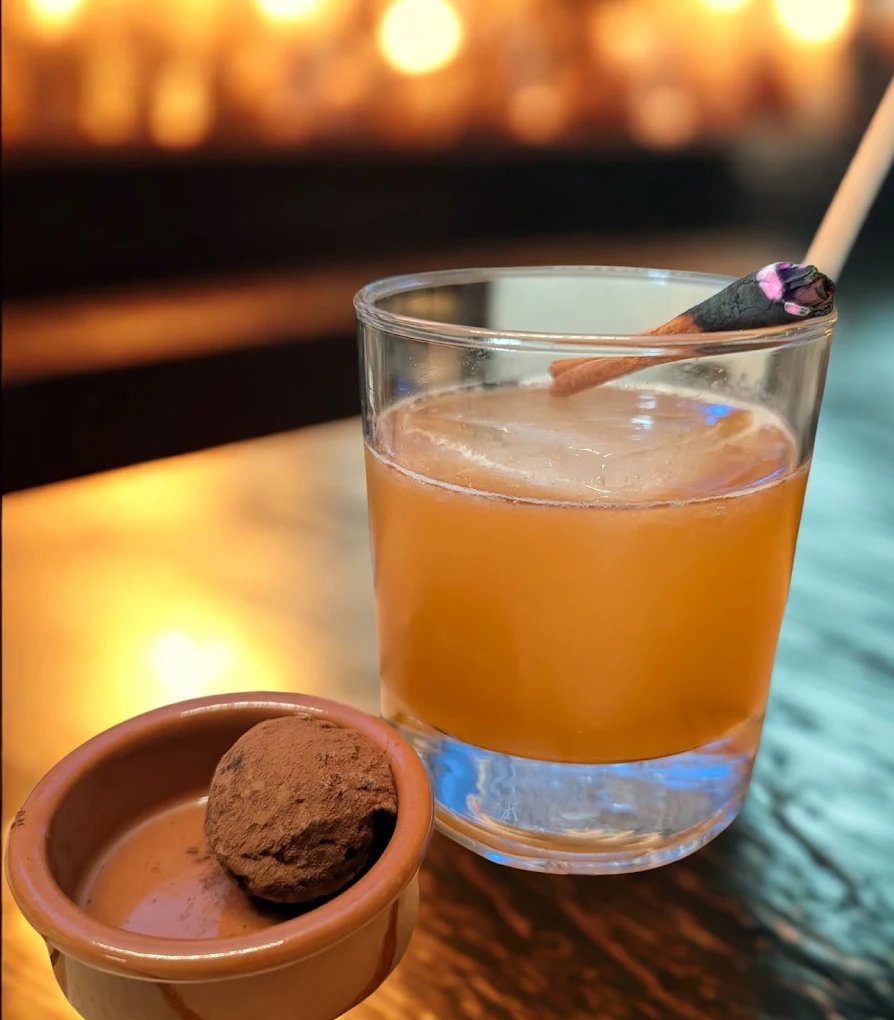 Cocktail ambré dans un verre bas, accompagné d'une truffe au chocolat